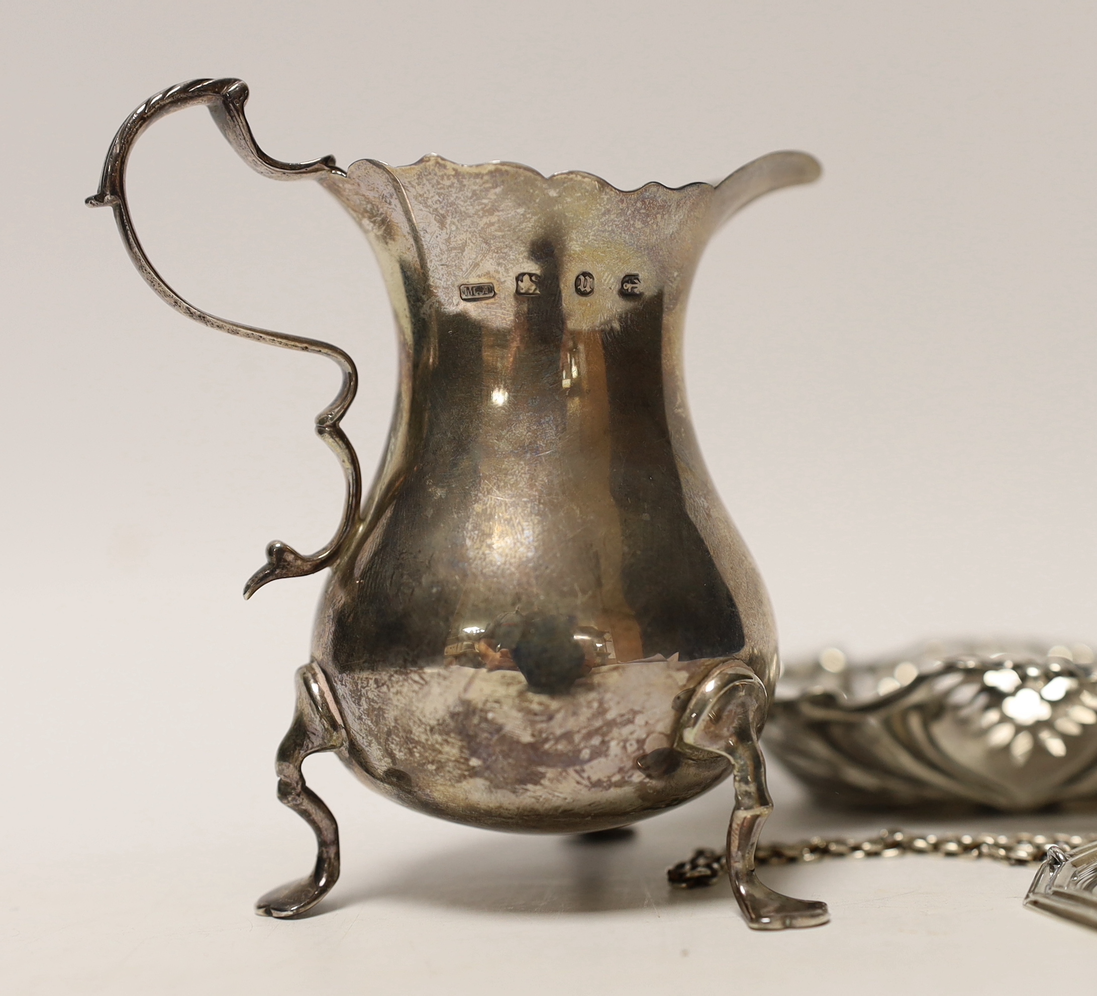 A late Victorian silver cream jug, Birmingham, 1894, 93mm, a repousse silver bonbon dish and a pair of modern silver wine labels.